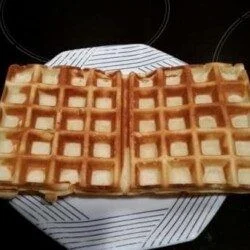 Wafer croustillant doré coupé en deux, posé sur une assiette blanche à lignes noires.