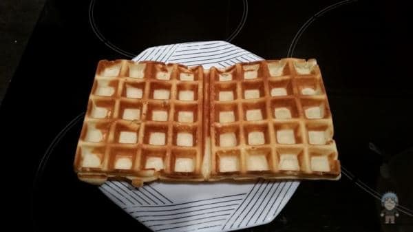 Wafer croustillant doré coupé en deux, posé sur une assiette blanche à lignes noires.