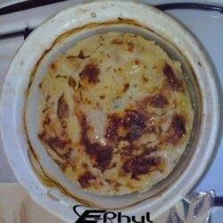 Ragoût de gratin dauphinois chaud dans un plat en céramique, prêt à être servi, avec un aspect doré et croustillant à la surface.