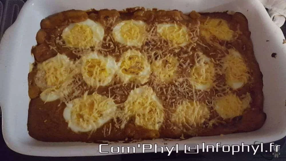 Oeufs gratinés avec sauce Mornay, garnis de fromage râpé, présenté dans un plat blanc.